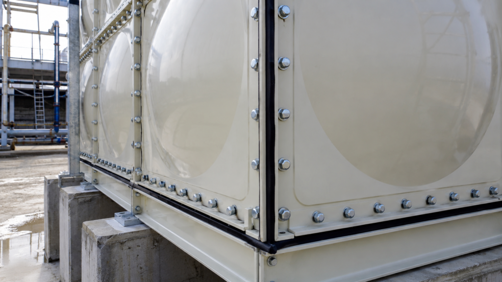 Close-up of enamel potable water tank panels showing glass-fused coating layers, bolts, and seam protection at an industrial water project site.